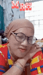 a woman wearing glasses and a head scarf with the letters mrh behind her
