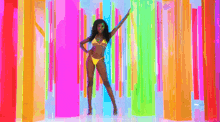 a woman in a yellow bikini is standing in front of a colorful wall .