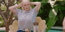 a woman is sitting in a wicker chair with her hands behind her head .
