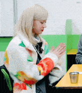 a woman wearing a colorful jacket sits at a table