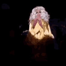 a woman wearing a yellow jacket and a pink scarf is standing in a dark room .