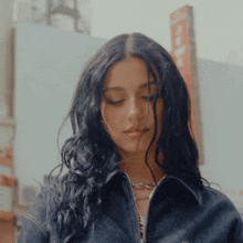 a woman wearing a denim jacket looks down at something