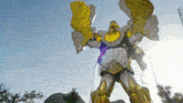 a statue of a robot with wings is standing on a rock