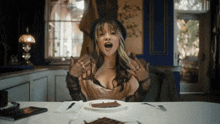 a woman is sitting at a table with her mouth open and a plate of food in front of her