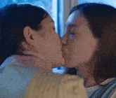 two women kissing in front of a window at night