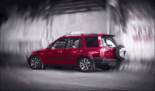a red suv with a spare tire on the back is driving through a tunnel