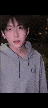 a young man wearing a grey hoodie with the letter d on the front
