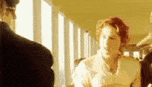 a woman in a white dress is standing next to a man in a black suit in a hallway .