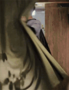 a person with long hair is standing in a room with a wooden wall behind them