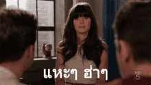 a woman in a white dress is standing in front of two men and talking to them in a room .