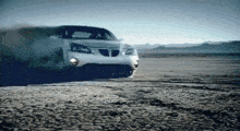 a white pontiac is driving through the desert