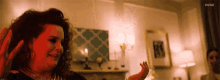 a woman is standing in a living room with a red light shining on her face .