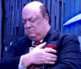 a bald man in a suit and tie is holding something in his hands