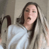 a woman with long hair is making a funny face in front of a mirror in a living room .