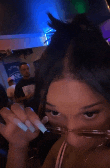 a woman with long white nails is wearing sunglasses in a room