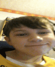 a young boy wearing a yellow shirt with the letter g on it smiles for the camera