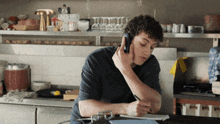 a young man talking on a cell phone while writing on a piece of paper