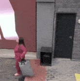 a woman in a pink outfit is carrying a gray bag