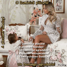 a woman in a white dress sits on a bed next to a little girl in a pink dress