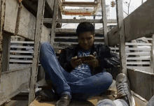 a man wearing a shirt that says rac is sitting on the ground looking at his phone