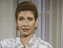 a woman wearing a floral shirt and earrings is making a face