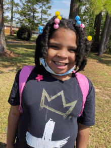 a little girl wearing a black shirt with a gold crown on it