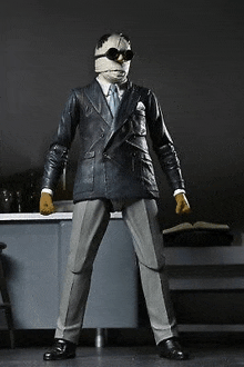 a man in a suit and mask is standing in front of a counter .