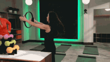 a woman in a black tank top is holding a hula hoop