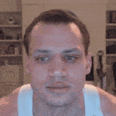 a close up of a man 's face with a white tank top