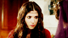 a woman wearing a red dress and a headband looks at the camera