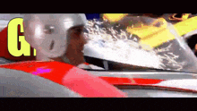 a man wearing a white helmet is driving a red car with the letter g on the bottom