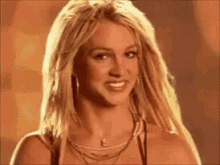 britney spears is smiling for the camera while wearing a necklace and earrings .