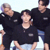 a group of young men are sitting next to each other wearing black shirts with the word lasty on them