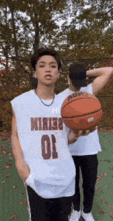 a man wearing a number 10 jersey holds a basketball next to another man