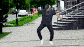 a man is dancing in front of stairs with a viggle.ai logo in the corner