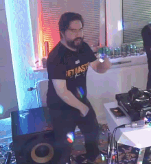 a man wearing a get waste shirt is dancing