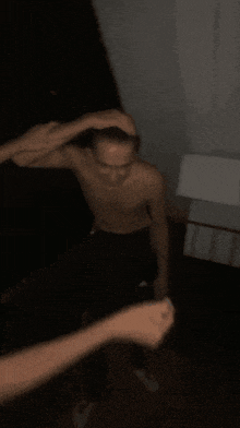 a man without a shirt is being held by another man in a dark room