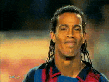 a man with dreadlocks is smiling and wearing a shirt that says ' barcelona ' on it