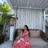 a woman in a red dress is sitting on a couch under a canopy