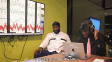 two men sitting at a table with a laptop that says sigsaver