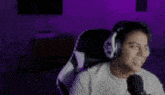 a man wearing headphones is sitting in a chair in front of a microphone in a room .