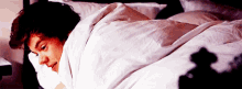 a man laying on a bed with a white blanket