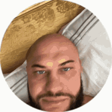 a bald man with a beard is laying on a bed with his head on a pillow