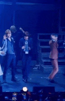 a group of people dancing on a stage with a blue background