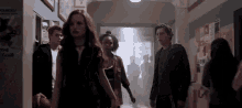 a group of people are standing in a hallway .