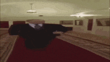 a man in a suit and tie is walking down a red carpet in a dark room .