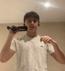 a man in a white lacoste shirt is holding a gopro camera