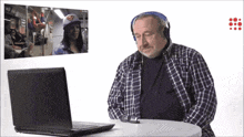 a man wearing headphones looks at a laptop screen