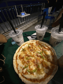 a pizza sitting on a table next to two drinks that say bubble tea