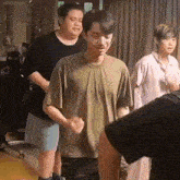a group of people are standing in a room . one of the men is wearing glasses .
